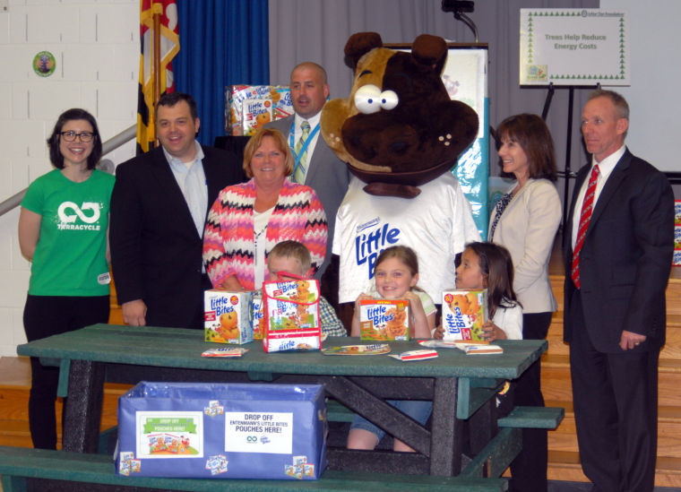 Brittany Thatcher, as the Entenmann's Little Bites mascot, presents a bench made out of recycled Entenmann's Little Bites pouches to the Oliver Beach Elementary school.